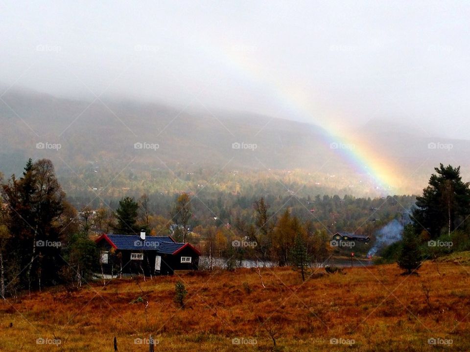 Sun, rain,cabin and a rainbow in the mountains
