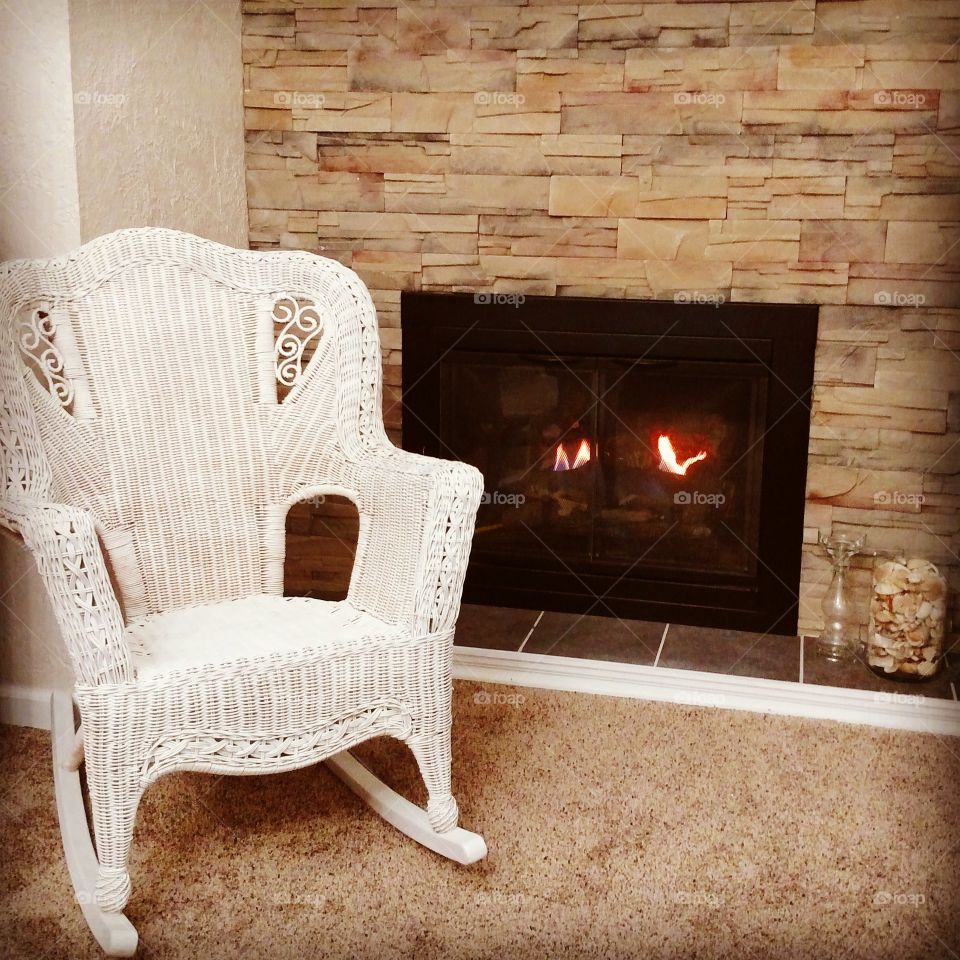 cozy fireplace and white wicker rocker