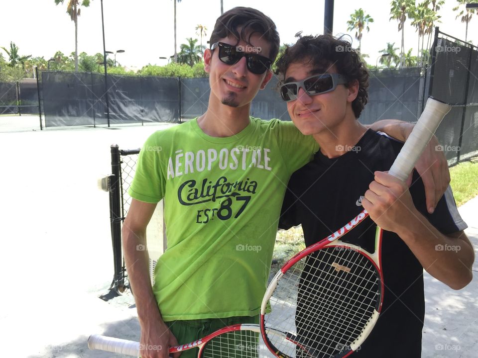 Portrait of teenage friends holding tennis racket in hand