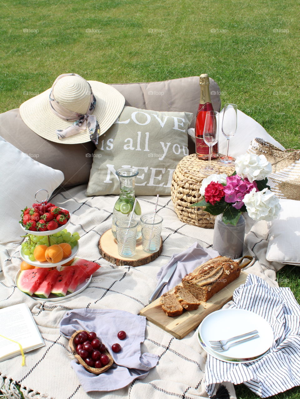 Spring picnic with fruits, cakes, book and champagne 