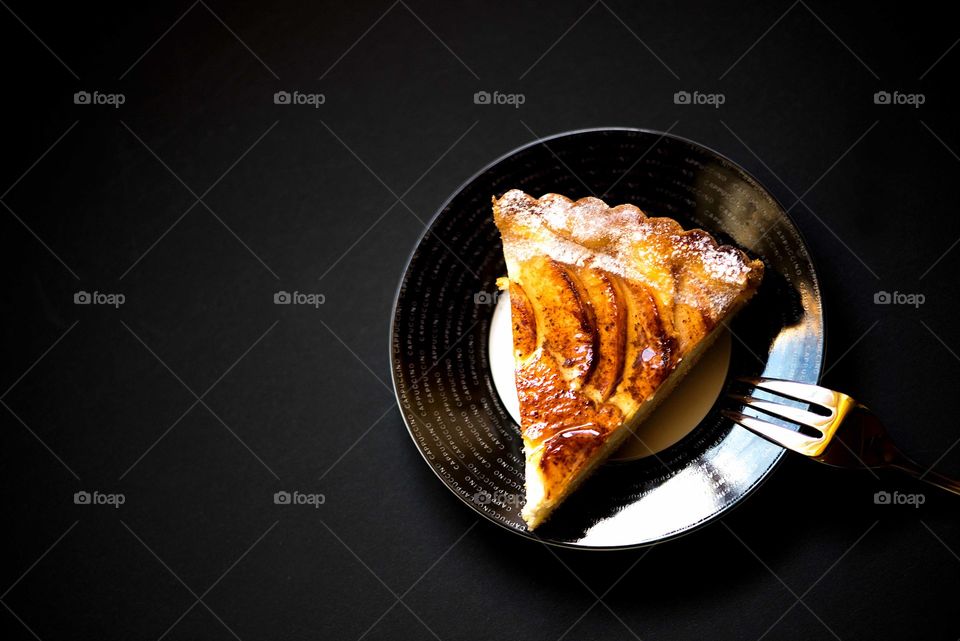 Apple pie slice isolated on black background, top view