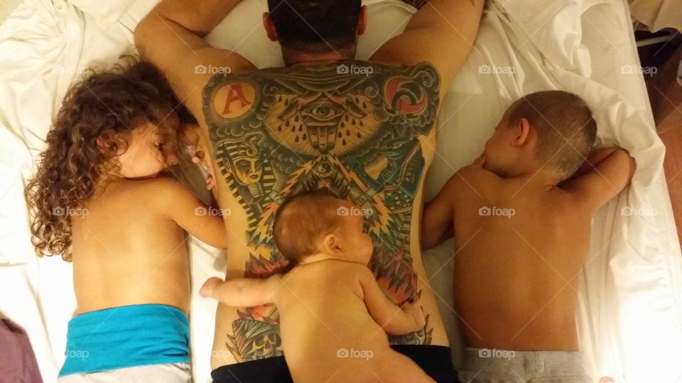 High angle view of father and children lying on bed