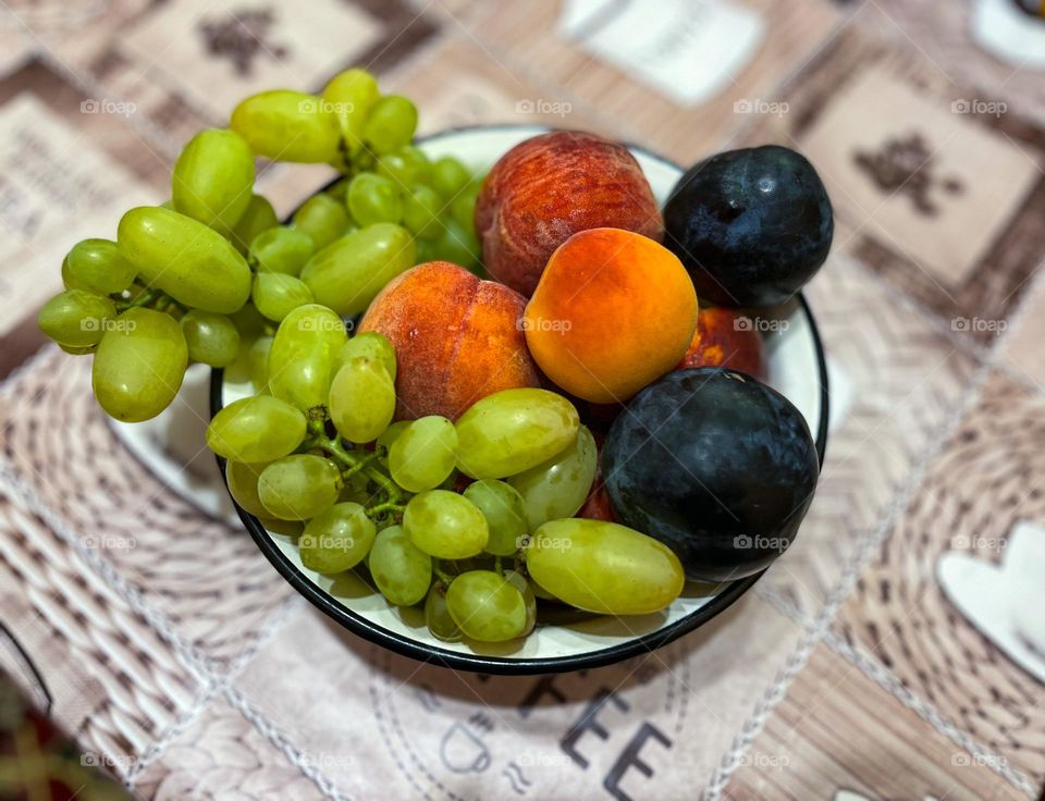 Circle bowl with grape, plums, peaches and apricots a