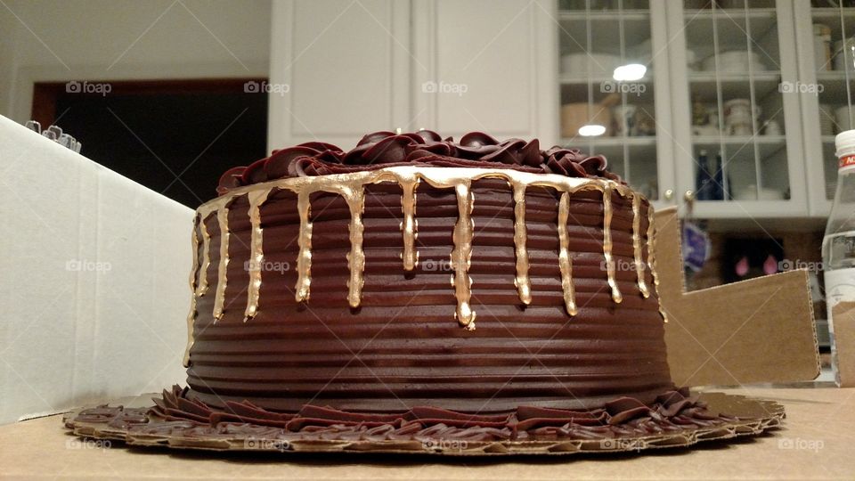 A gorgeous fudge cake with golden drip around the edges.
