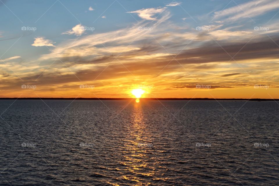 Golden hour sunset with clouds over the ocean reflection on water