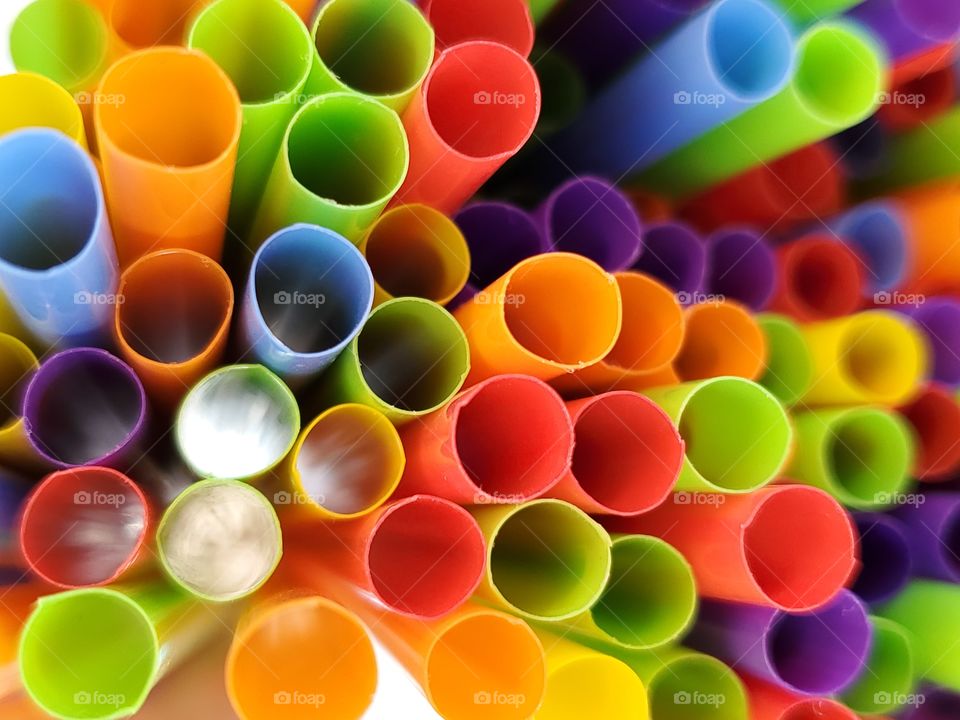 A pop of color from a top view of colorful plastic straws at various heights and with light peering through some of them.