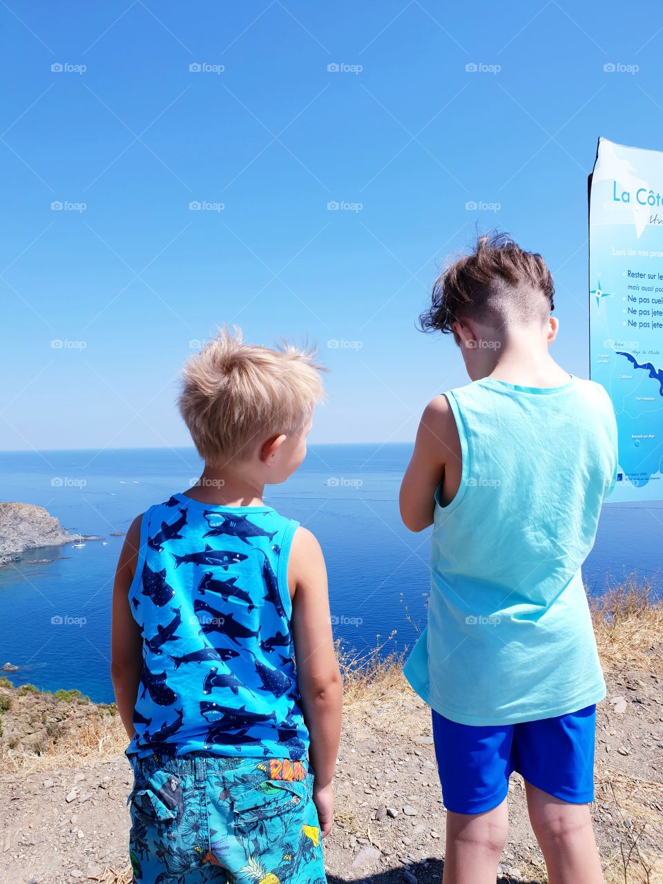 Two boys standing at viewpoint looking out over the ocean
