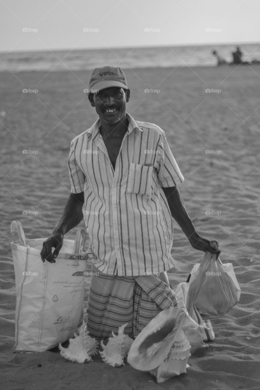 Asian man selling seashells at beach