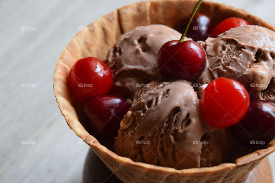 Ice cream scoops in cone with cherries