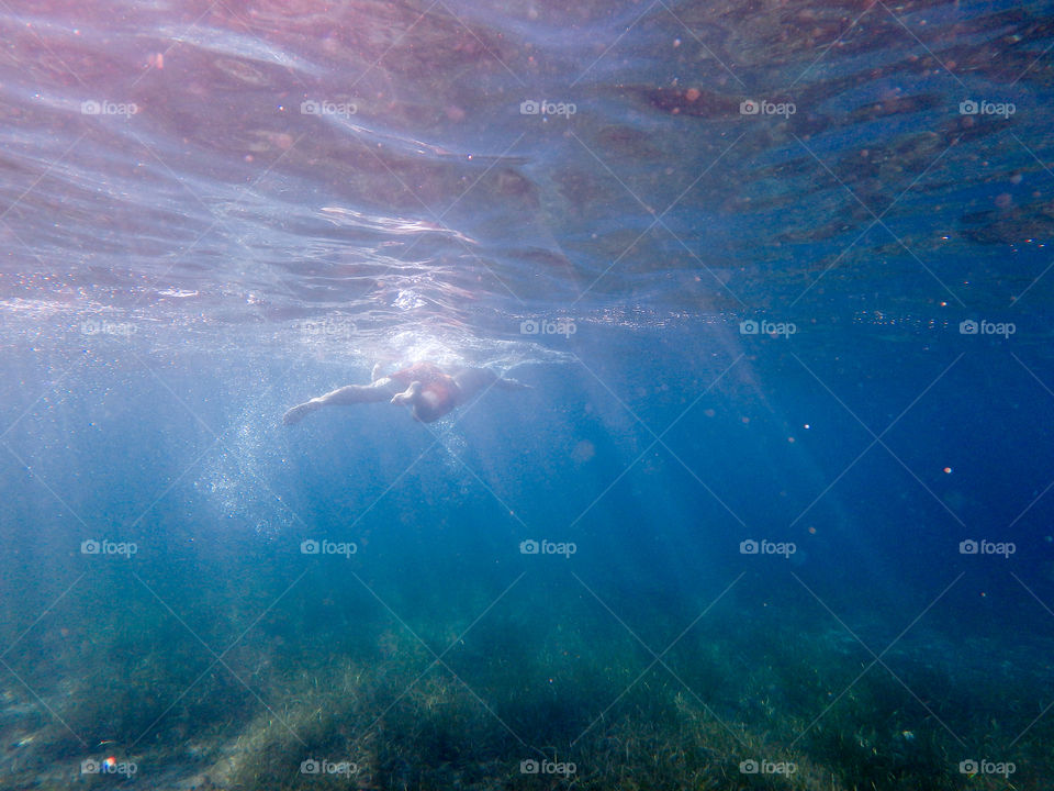 Man diving in the ocean, male underwater smiling,swimming and relaxing in big blue sea with his waterproof camera