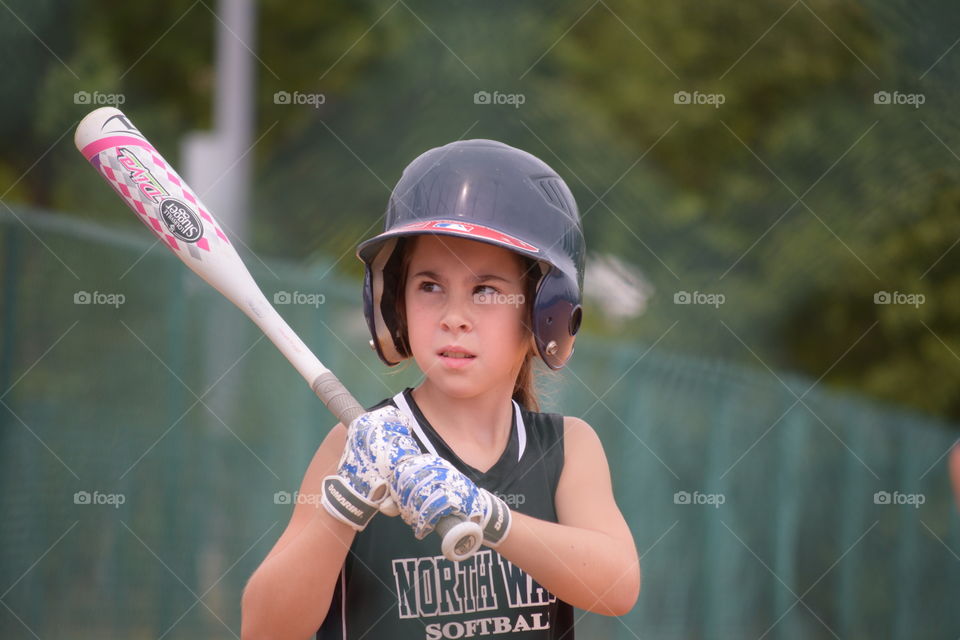 Little girl holding baseball bat wearing helmet
