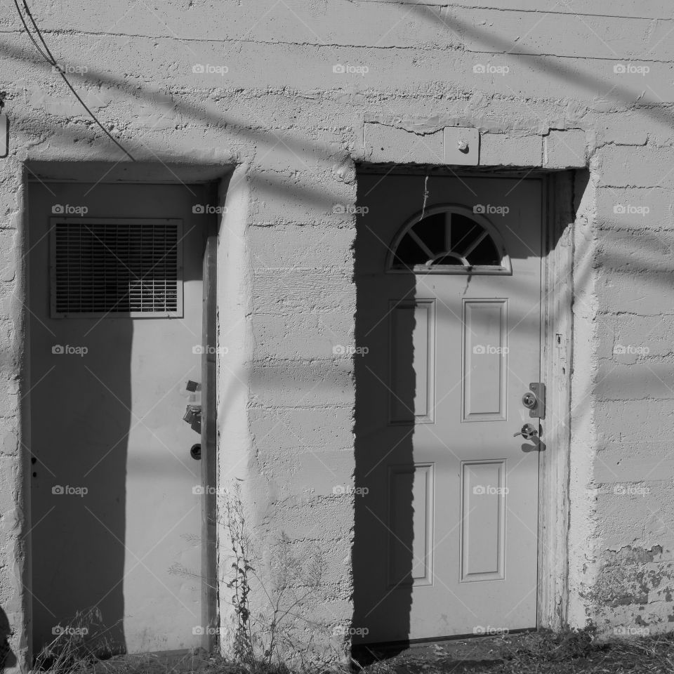 The side of an old concrete building in a city with doors on a sunny summer day. 