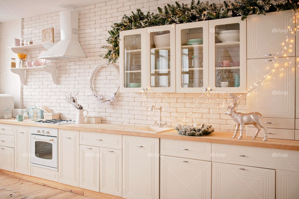 Festive winter cozy kitchen interior with garlands, decorations and gifts.  Christmas dinner at the decorated table.