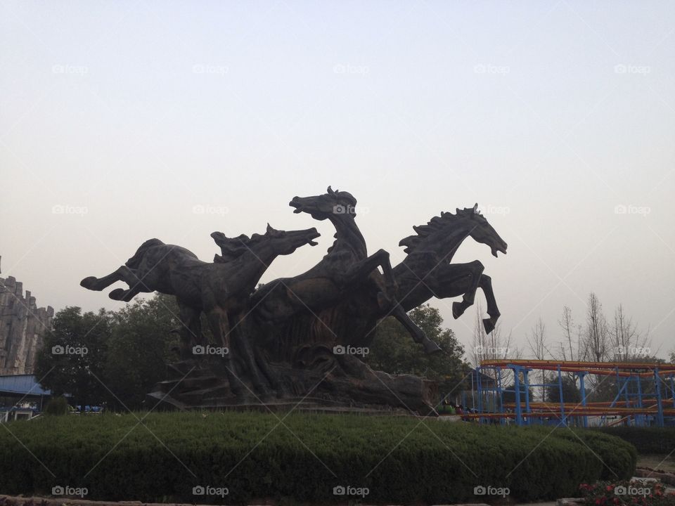 A statue of horses on a flowerbed in a Park