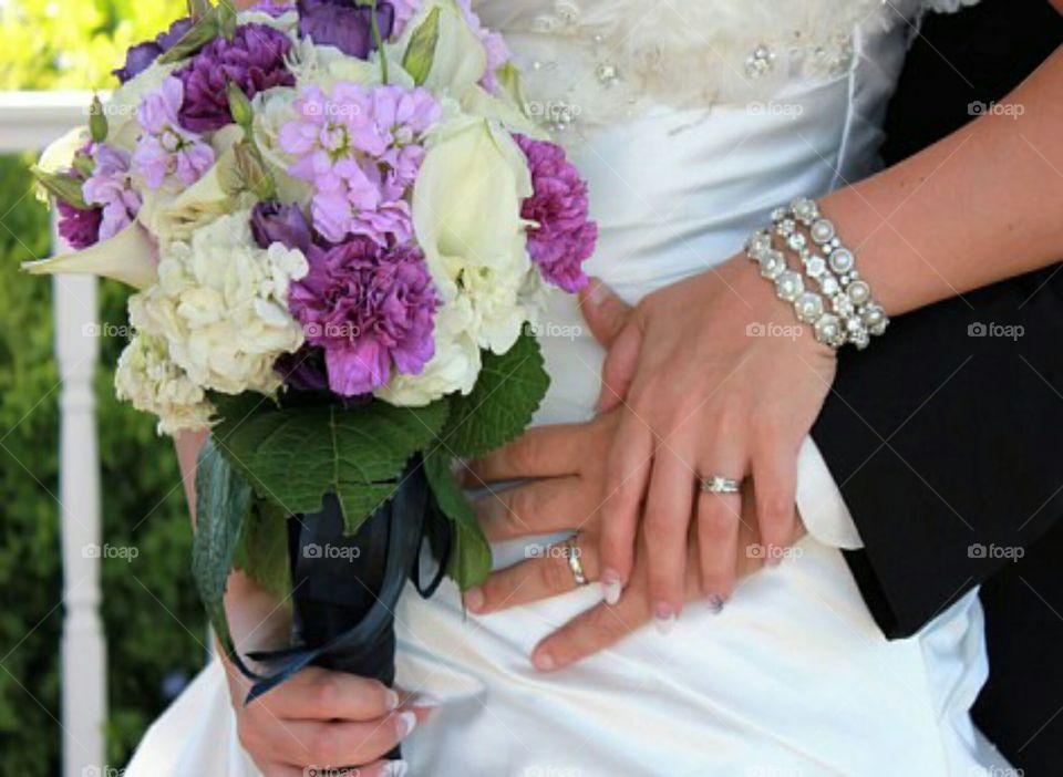 Joined in marriage by wedding rings.