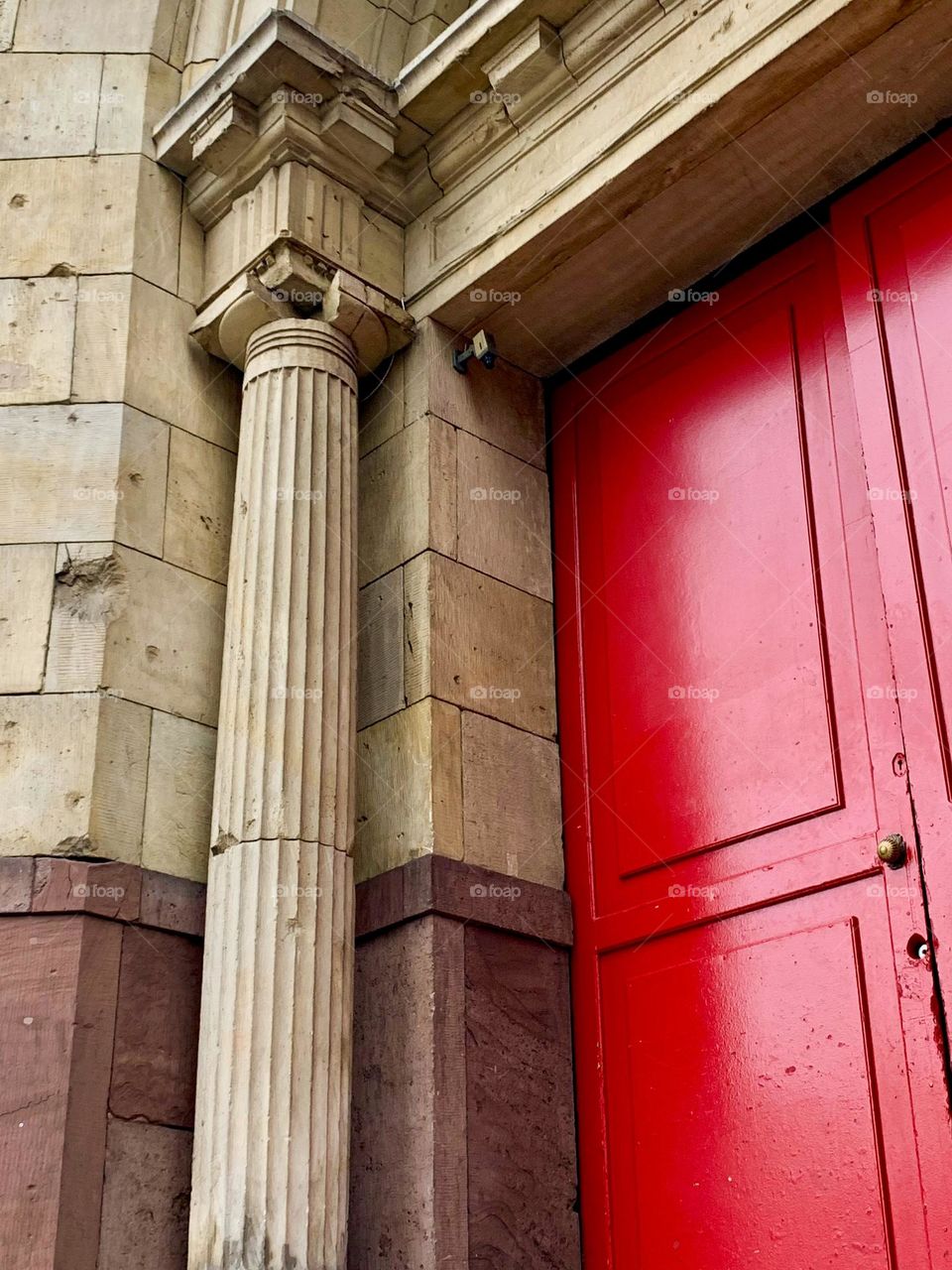 Old big wooden bright red door, portal with columns, old architecture, stone textures 