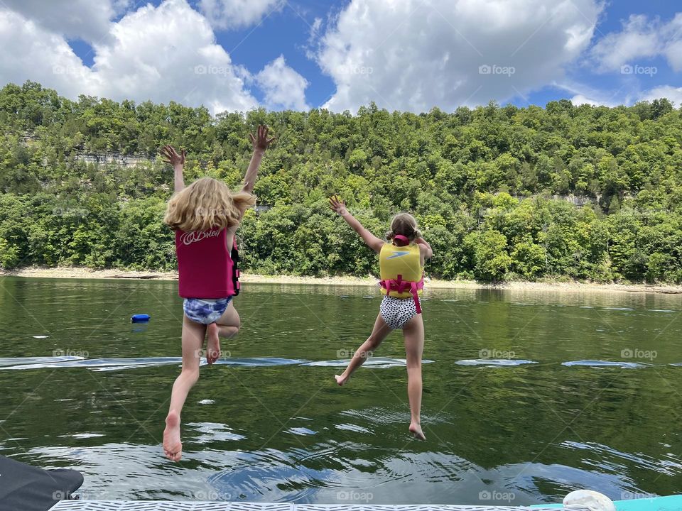 Two best friends jumping into the lake