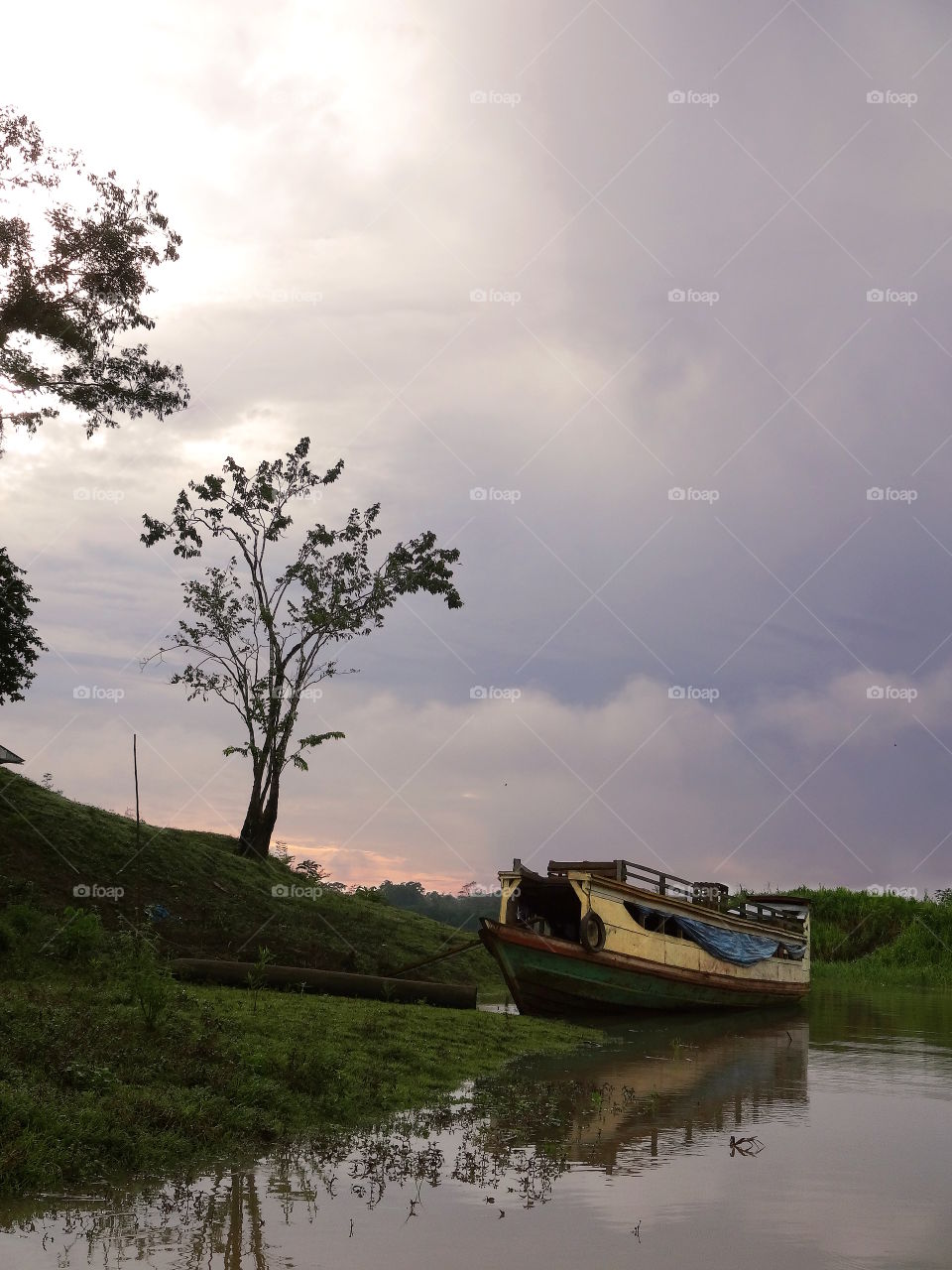 Decrepit house boat, amazon rainforest, 30 miles from Iquitos Peru. Purple stormy foreboding sky with orange sunset. Gloomy scene.