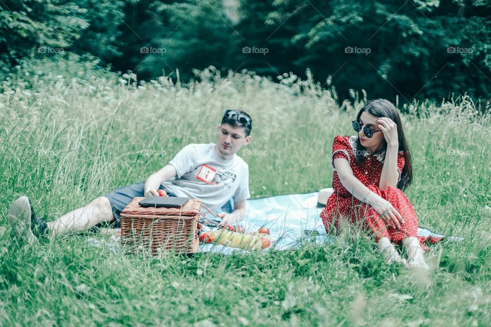 One beautiful young caucasian sad couple is resting on a picnic in the park without talking to each other,close-up side view. Family picnic time concept.