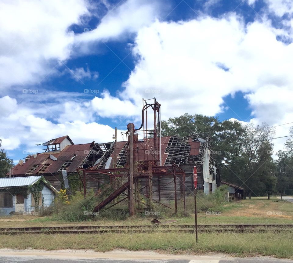 A very old   falling down building , contrasted against a gorgeous puffy cloud blue sky in our town in the country. 