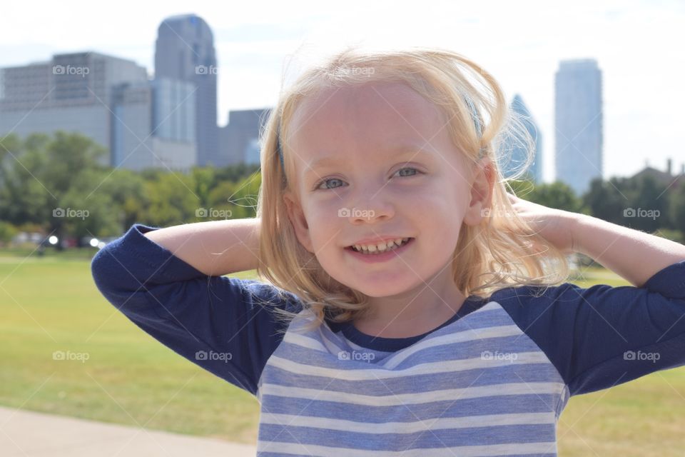 Girl at city park. Toddler and city skyline