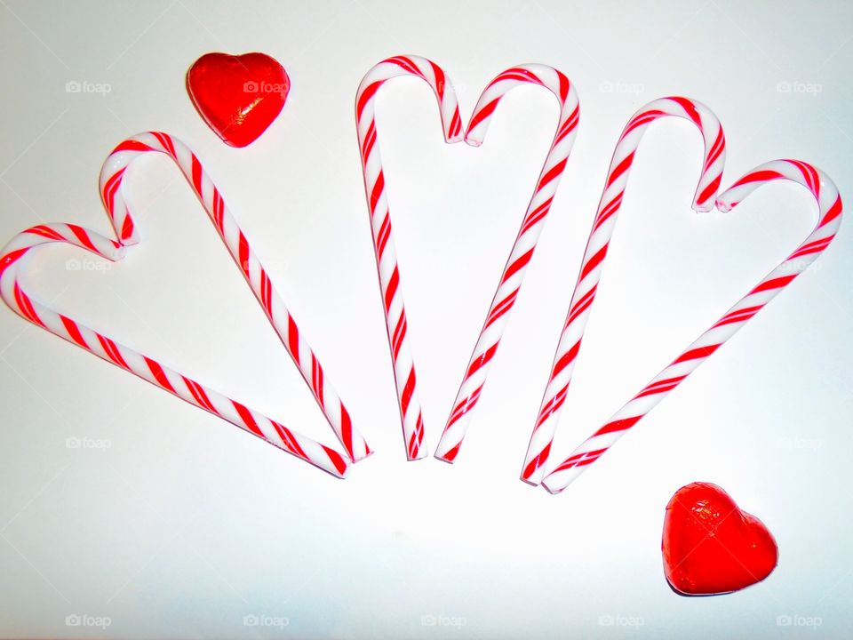 Hearts made of candy canes with chocolate hearts on white background