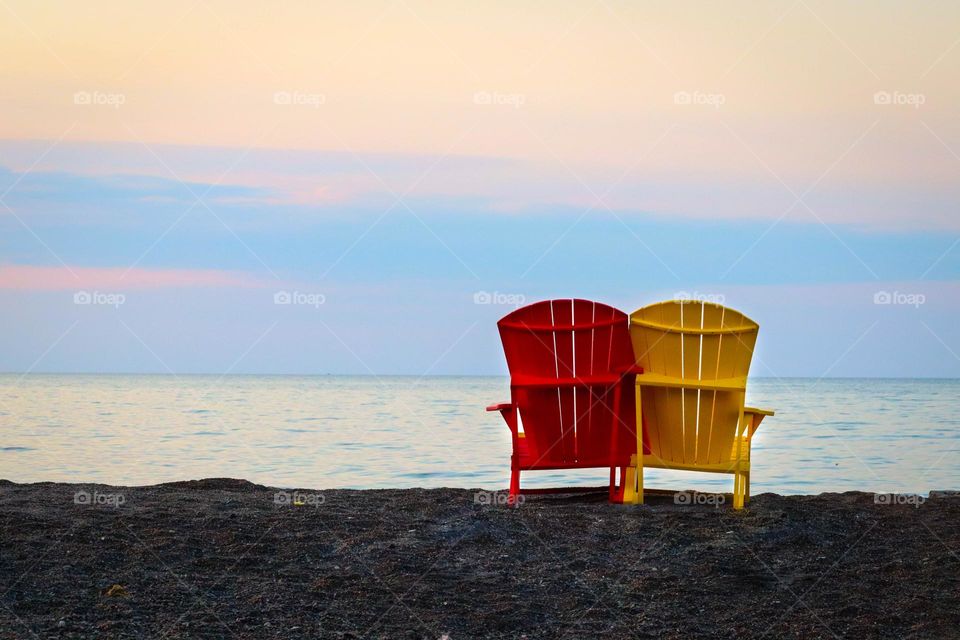 Sunrise on a beach: two colourful beach chairs side by side