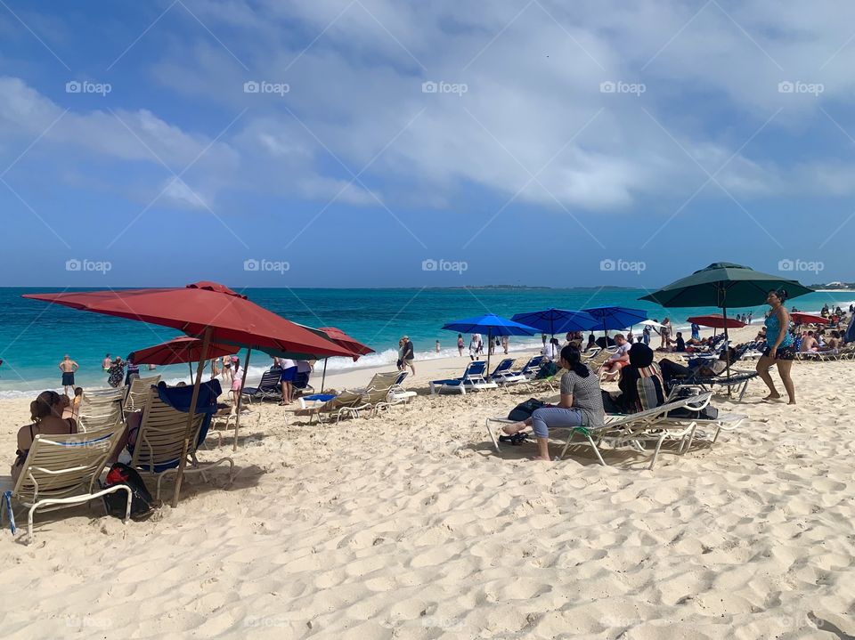 People on the beach with lawn chairs and umbrellas looking at the water