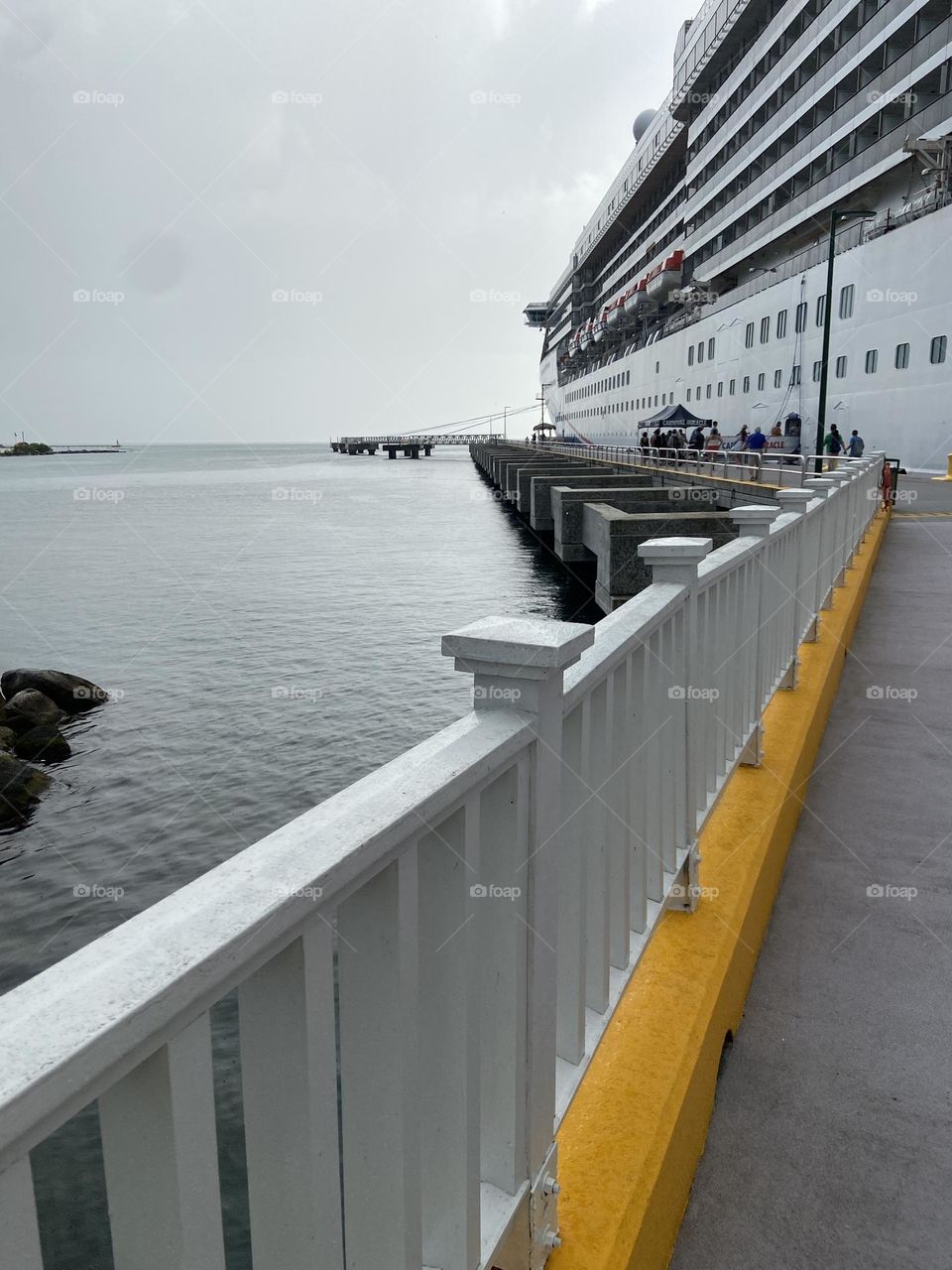 A bright yellow curb guiding the way to a white cruise ship on a cloudy day.