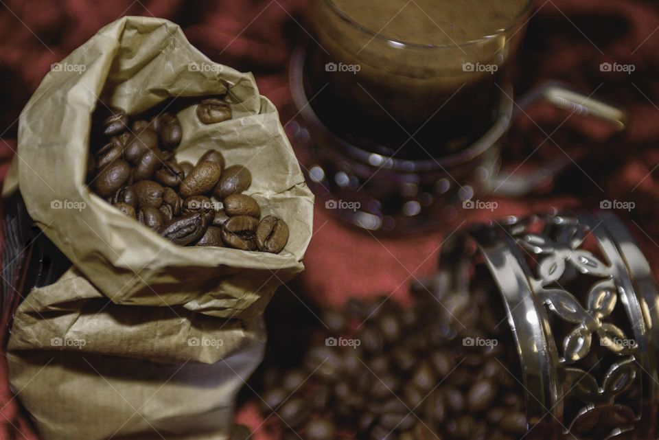 Fragrant coffee beans are scattered on a red background. Roasted coffee beans close up.