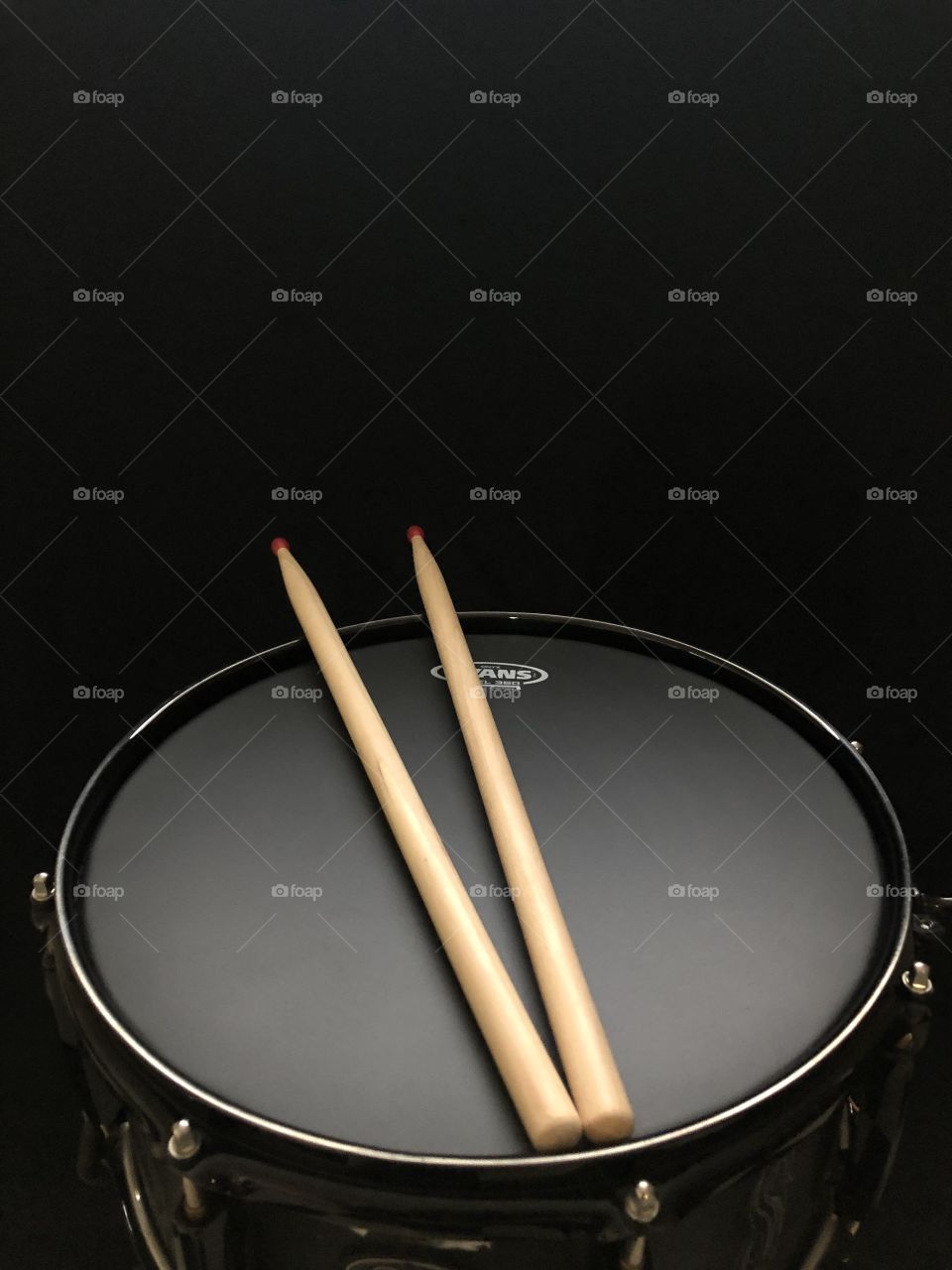 Black snare drum with drum sticks and black background 