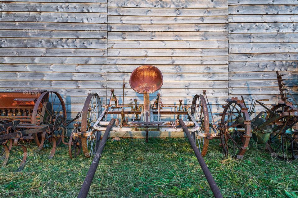 Old farm machines against wooden barn.
