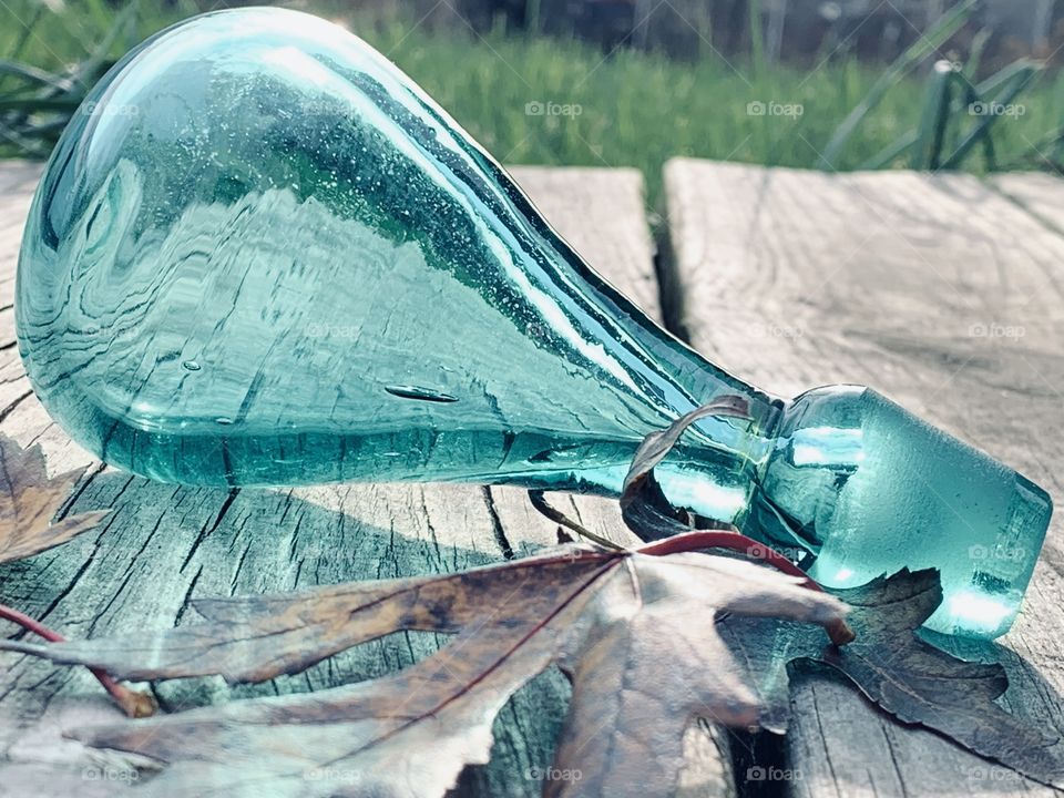 A bauble in the mid-morning sun. Glass, with the Autumn leaves, reflecting in the sun. 