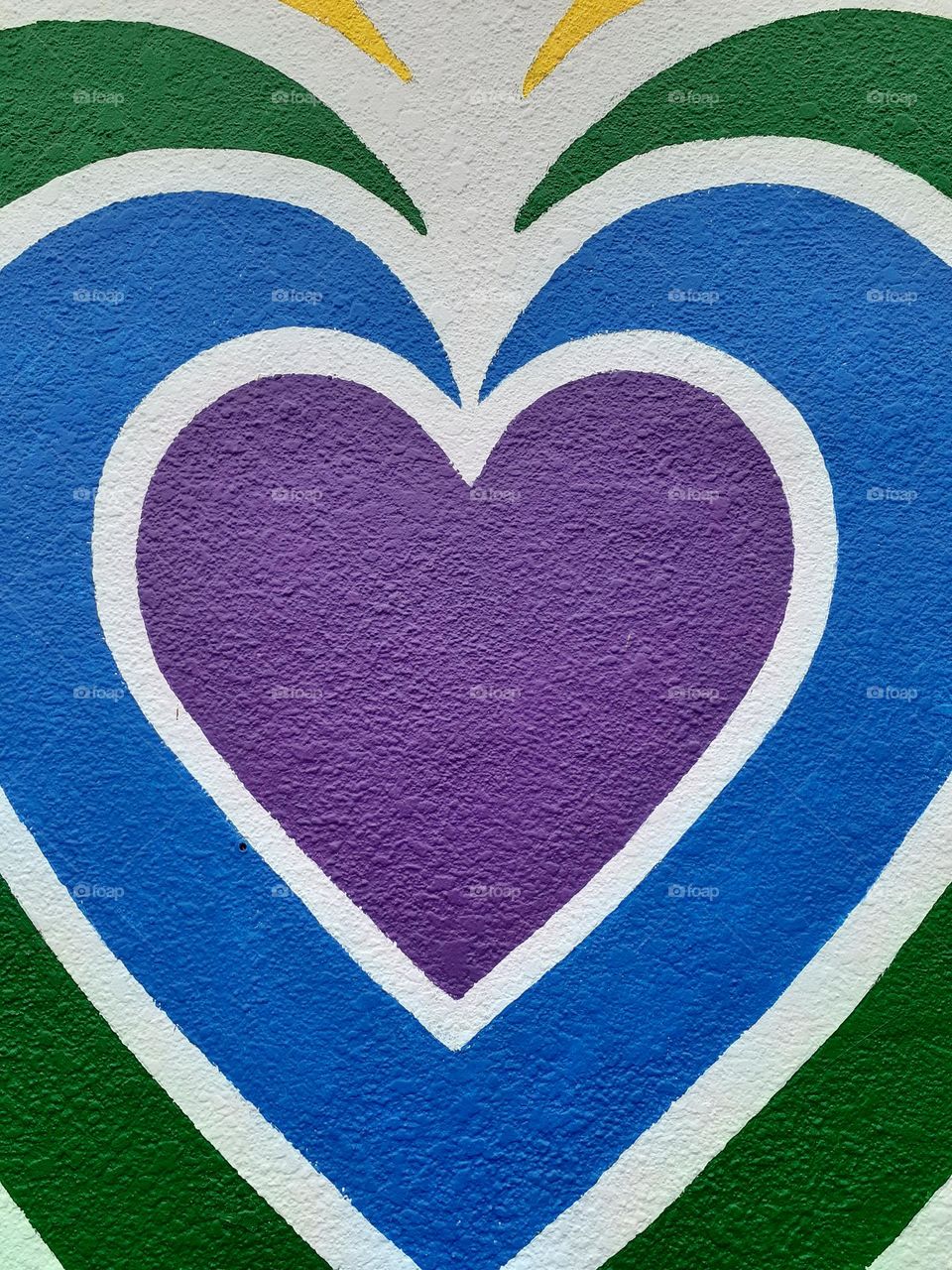 A mural with purple, white, blue, and green hearts painted on it. It is painted in remembrance of the victims and the survivors of the Pulse shooting.