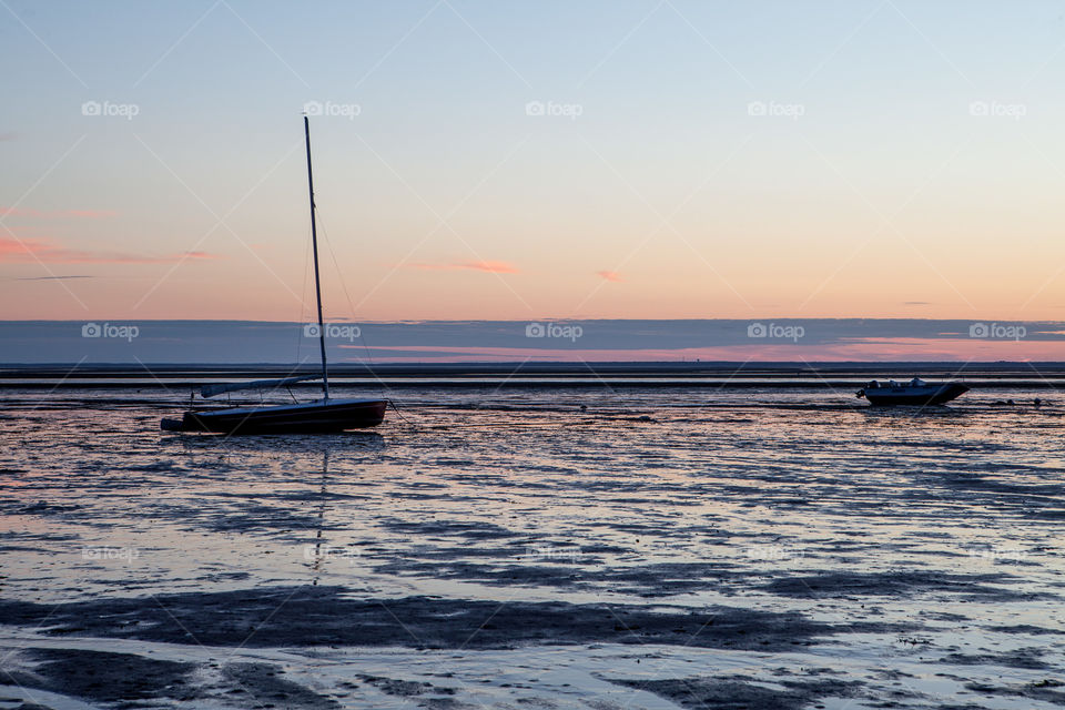 Very low tide at dawn in cape cod with a sailboat