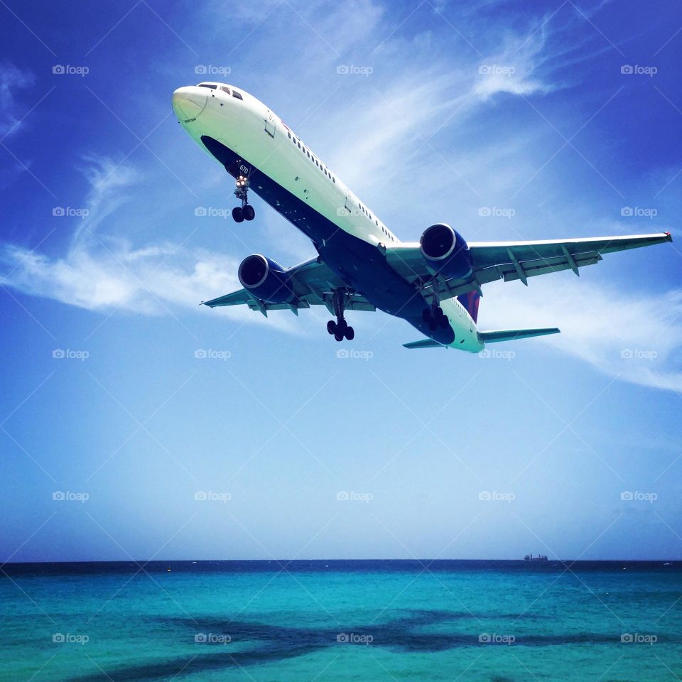 Plane flying over the ocean, perfect plane shadow, close to the plane landing, close to the air strip, Caribbean island flights, Maho beach in St. Maarten, view from the beach