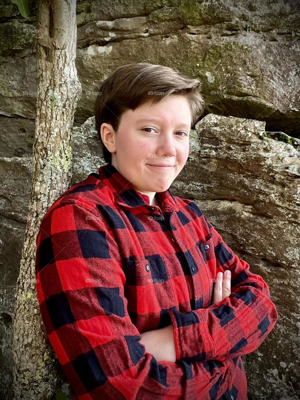 A handsome young man leaning on a tree 