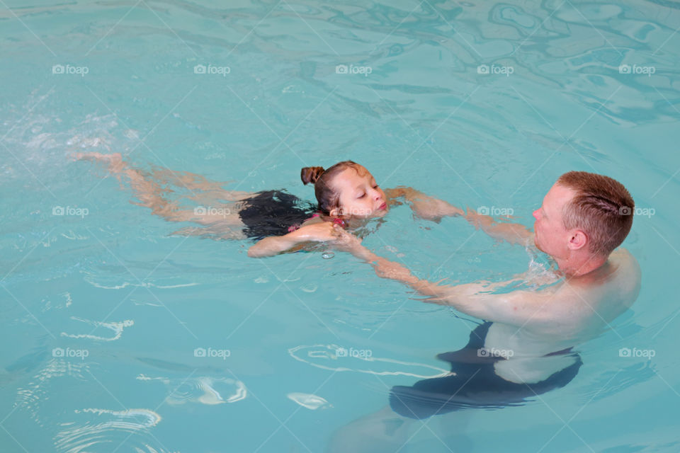 Father teaching his daughter how to swim