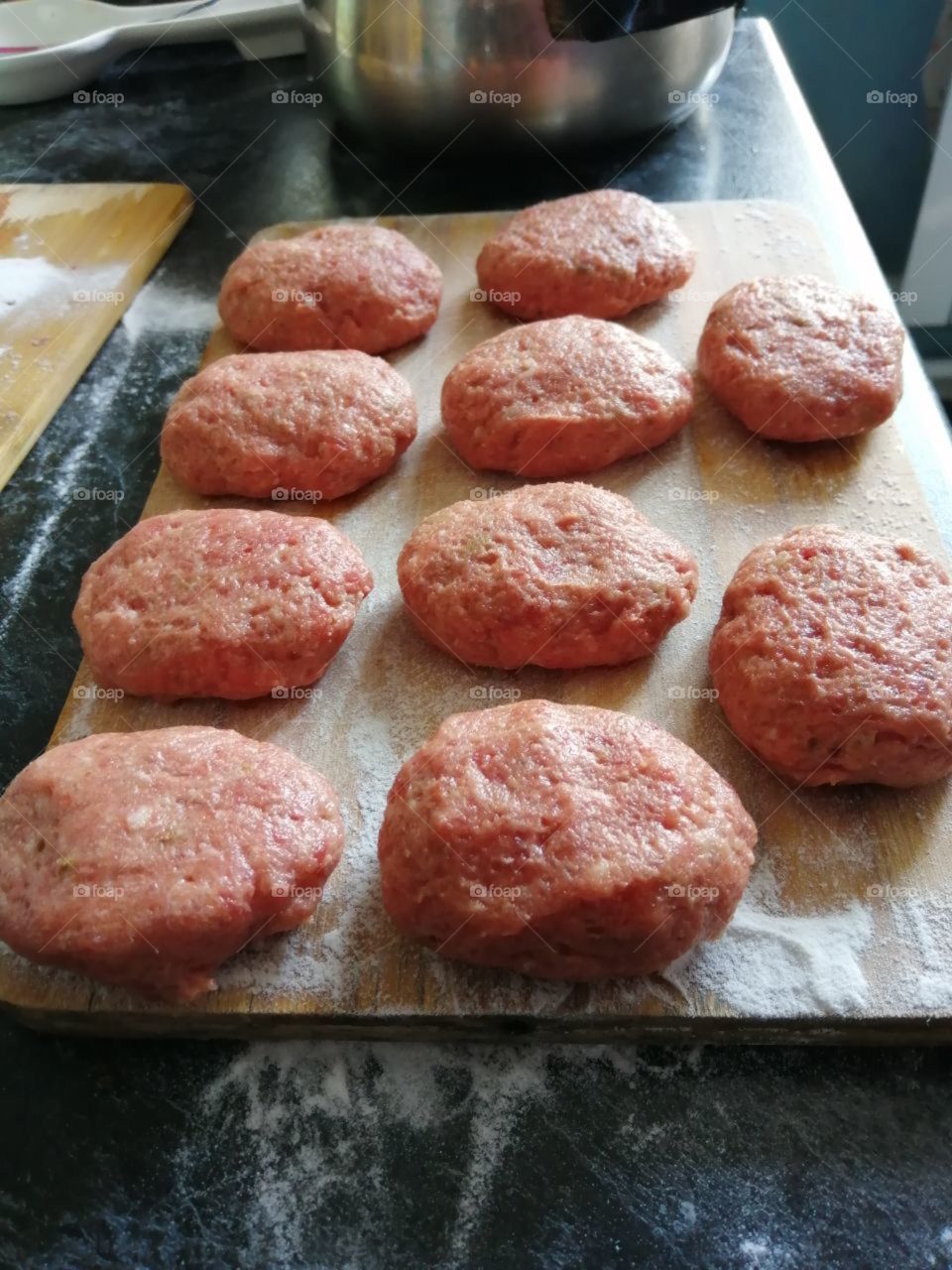 Uncooked meatballs (minced meat) on a wooden cutting board
