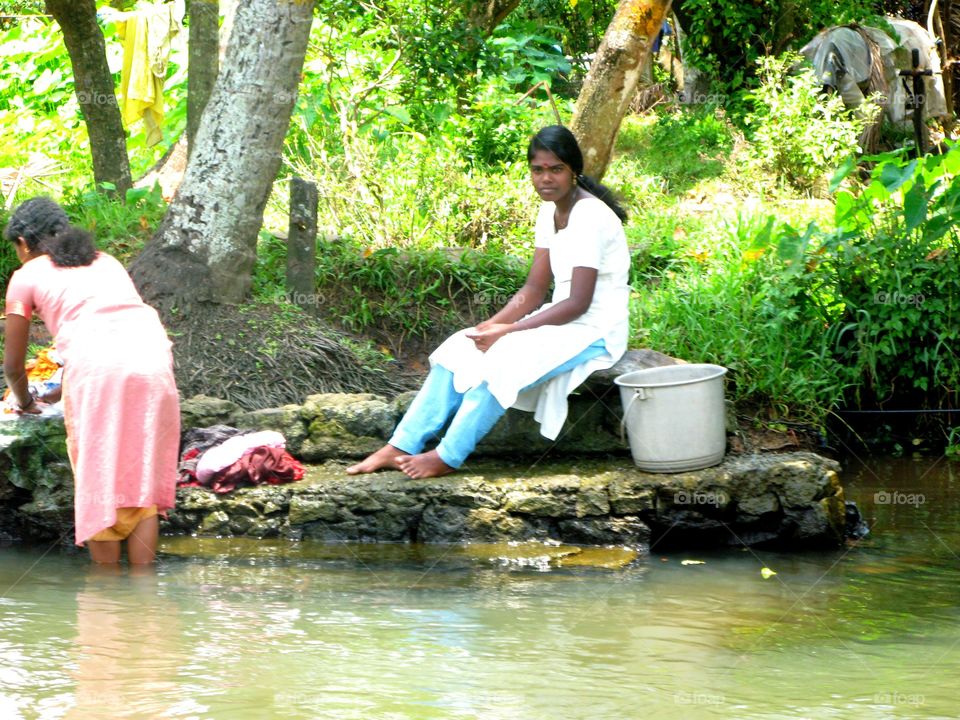 Beautiful Indian Washer Girl taking a rest into the backwater scenery of Alaphuzza, Allepey, Kerala, India