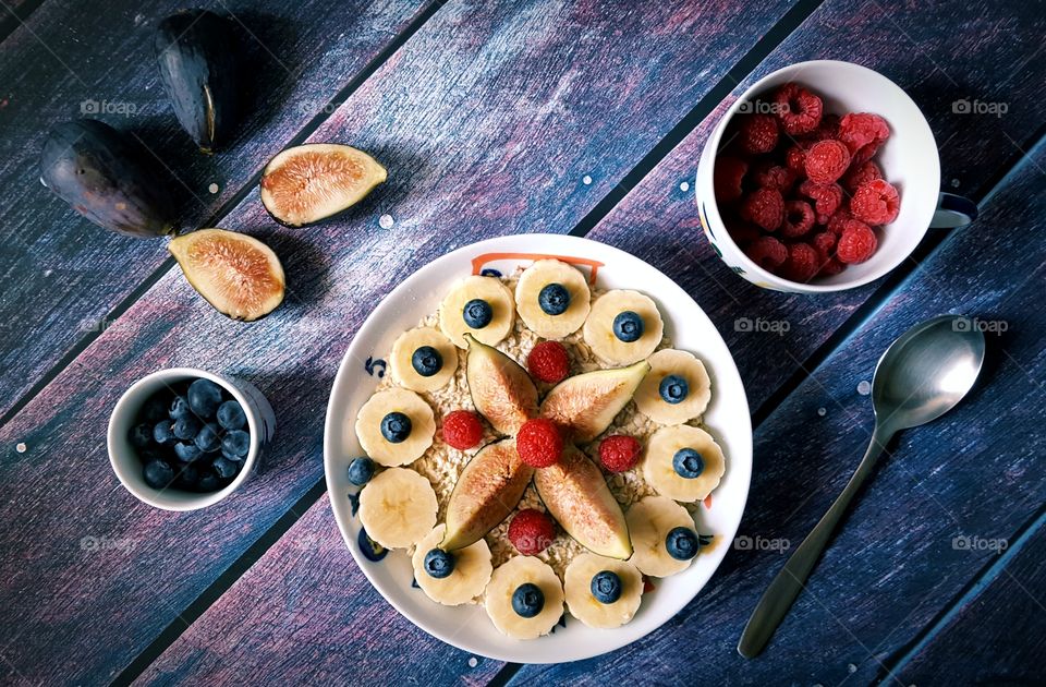 Ingredients for a healthy breakfast: oat flakes, banana, figs, raspberries and blueberries.