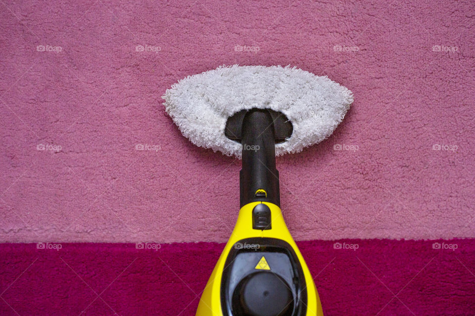 Yellow stem cleaner is standing on the pink carpet, top view