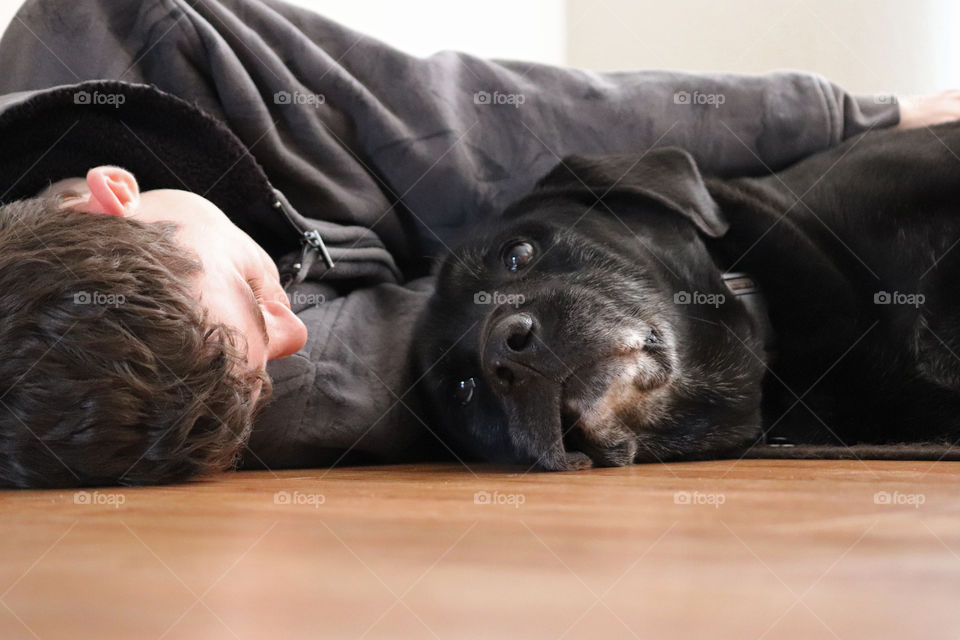 Young teen cuddling black labrador