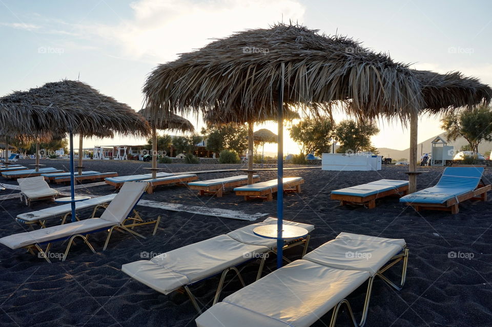 Low sun through umbrellas at Perissa Beach, Santorini, Greece 