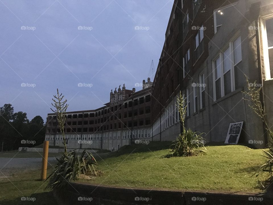 A creepy sanatorium L-shaped building at dawn with a keep out sign