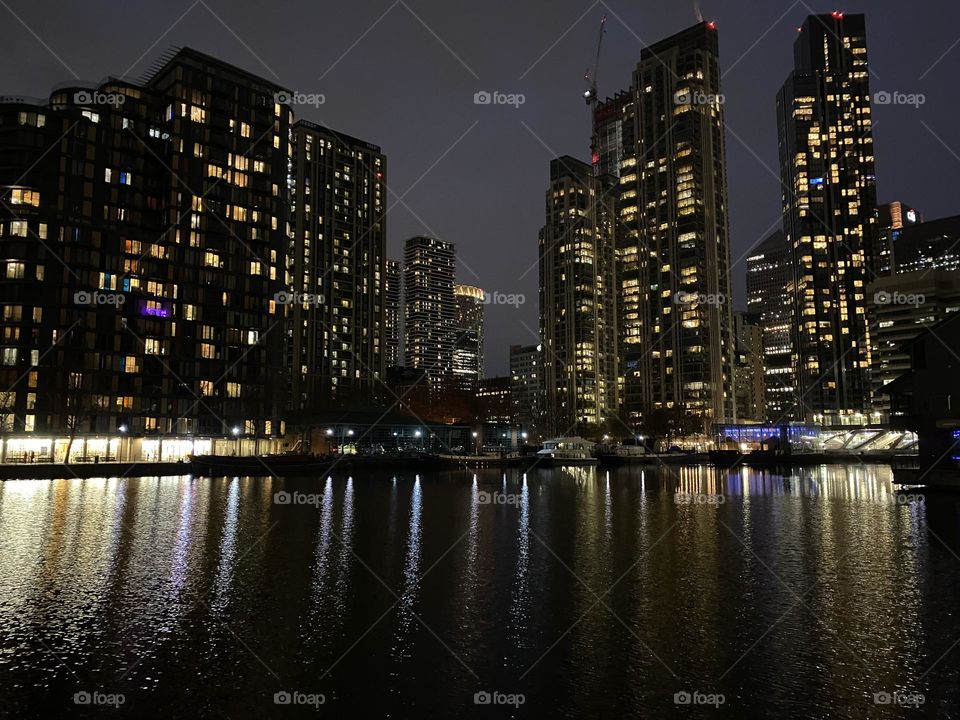 Buildings with illuminated windows during evening and reflection at water