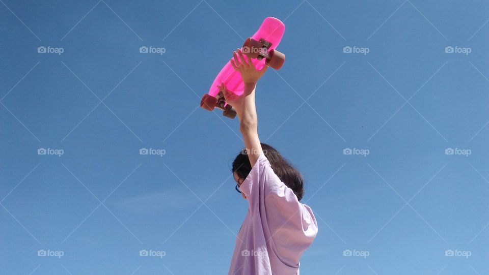 Young girl holding  pink skate board