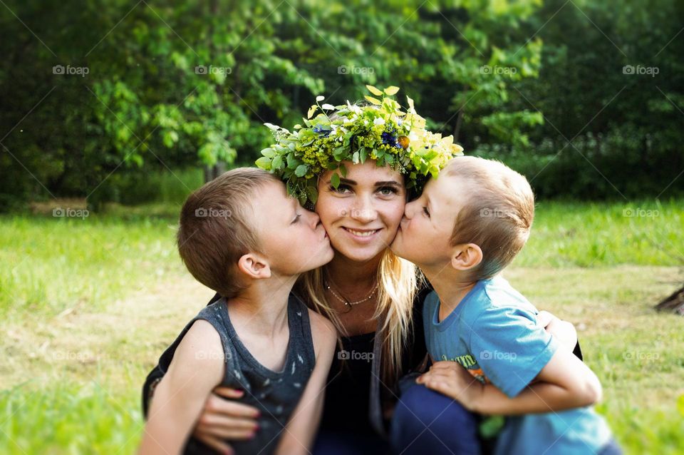 single mother and her two sons. boys giving a kiss on mothers cheeks