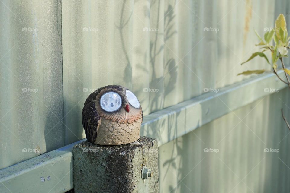 Garden Own Sculpture with LED lights for eyes, sitting on a stone post
