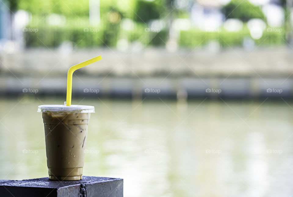 Iced coffee in a glass On the steel rod Blur background river.